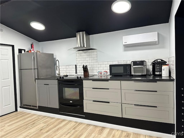 kitchen with wall chimney range hood, dark countertops, a wall mounted AC, a sink, and black appliances