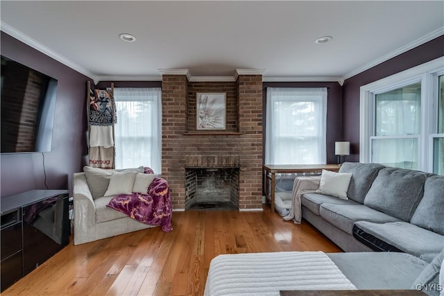 living area with crown molding, a wealth of natural light, and hardwood / wood-style flooring