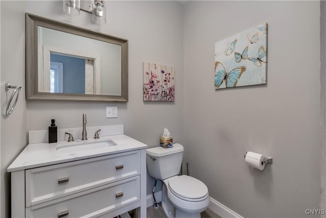 half bath featuring vanity, baseboards, and toilet