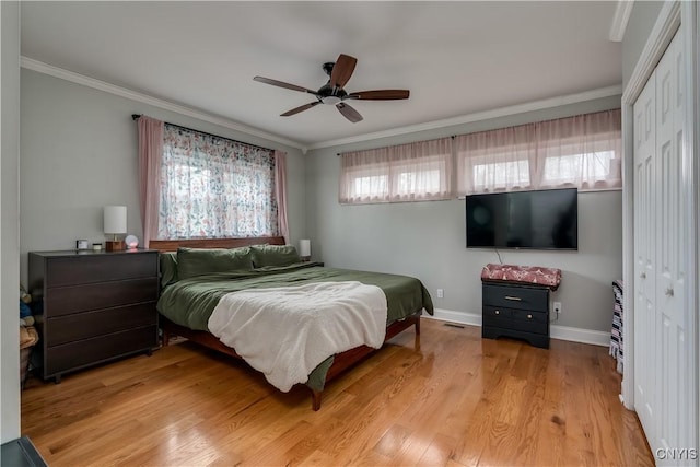 bedroom featuring a closet, baseboards, ornamental molding, and light wood-type flooring