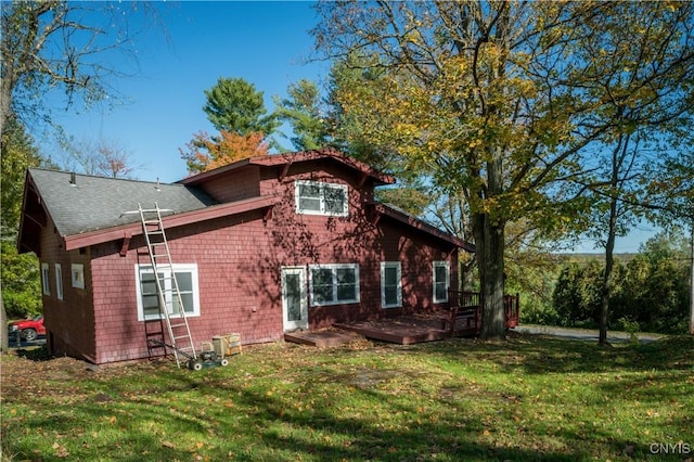back of house with a wooden deck, a shingled roof, and a yard