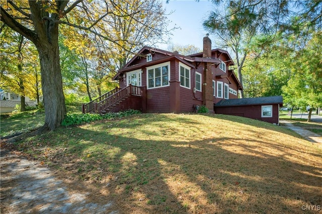 view of side of home with a chimney and a yard
