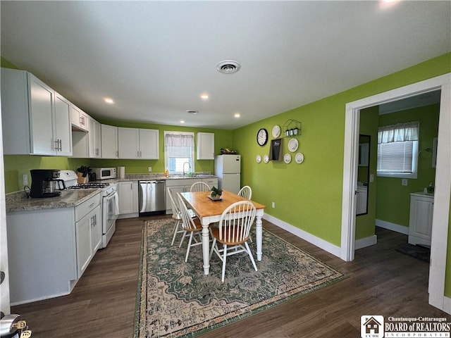 kitchen featuring visible vents, baseboards, white cabinets, and white appliances
