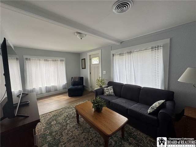 living room with plenty of natural light, beam ceiling, wood finished floors, and visible vents