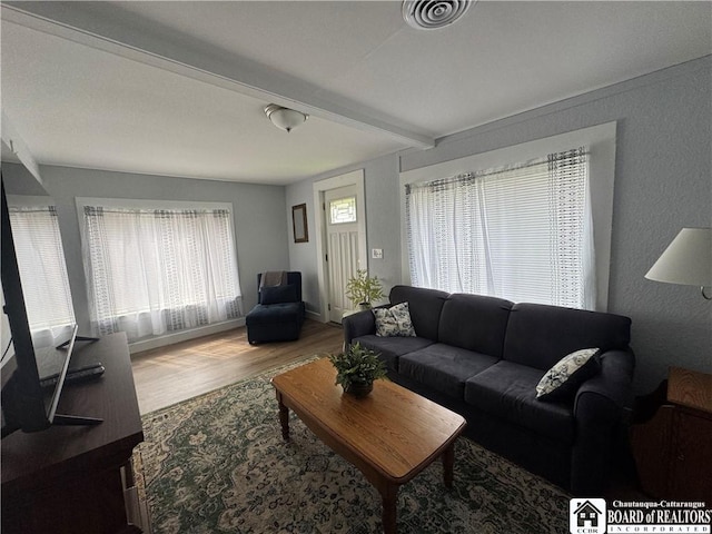 living area featuring a textured wall, visible vents, and wood finished floors