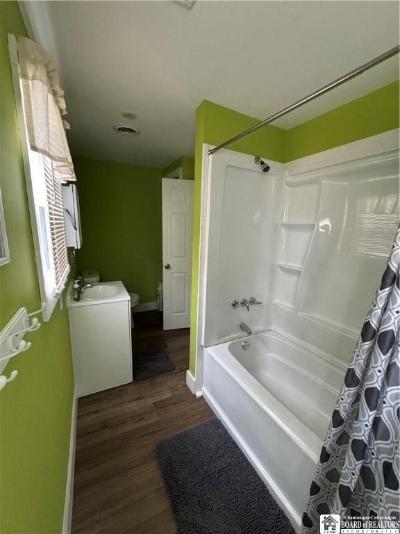 full bath with shower / bath combo, vanity, toilet, baseboards, and wood finished floors