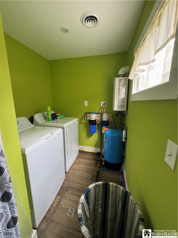 clothes washing area with water heater, laundry area, independent washer and dryer, and visible vents