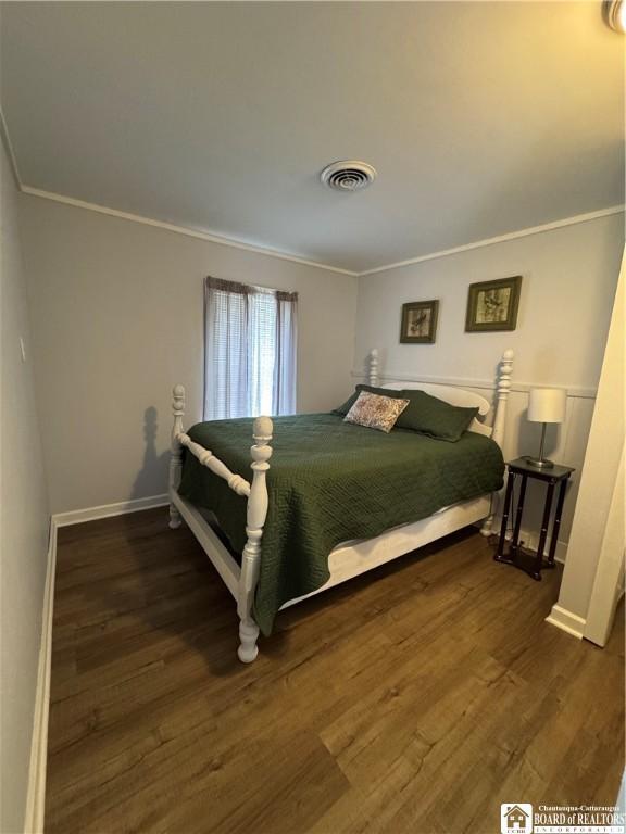 bedroom featuring crown molding, baseboards, visible vents, and wood finished floors
