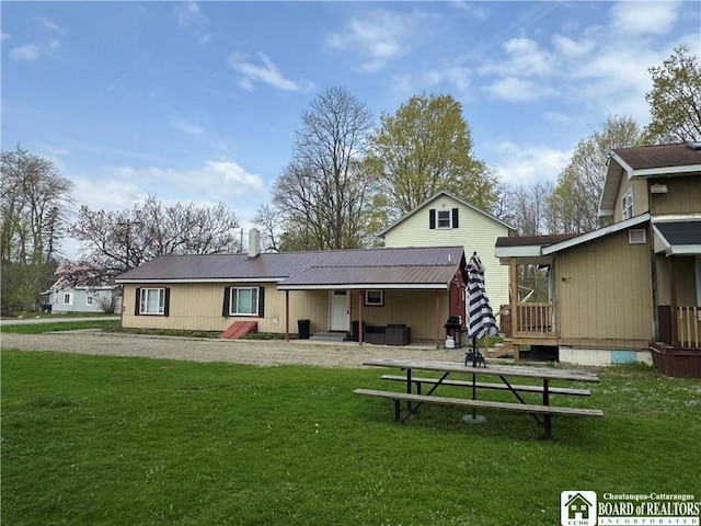 rear view of house with a yard, a chimney, and metal roof