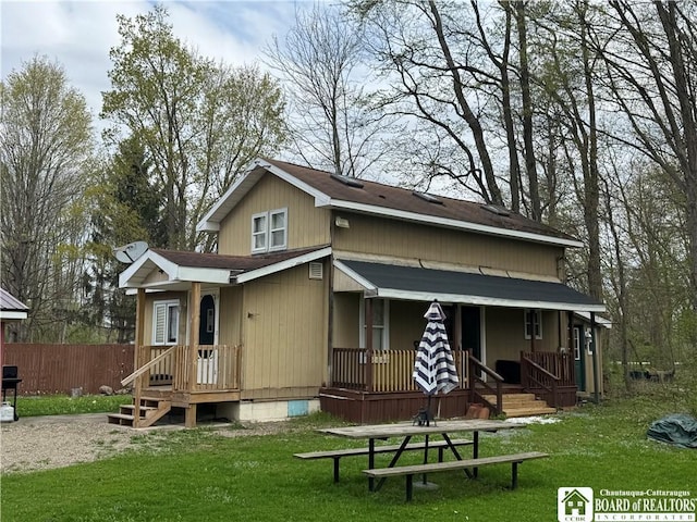 rear view of house featuring a lawn, crawl space, fence, and covered porch