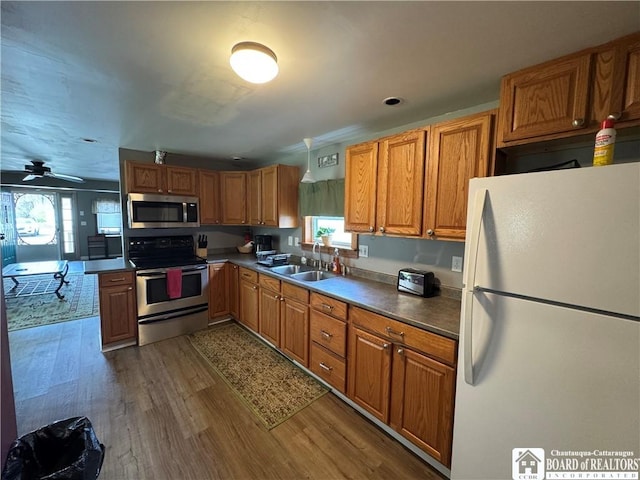 kitchen featuring brown cabinetry, a sink, a wealth of natural light, and stainless steel appliances