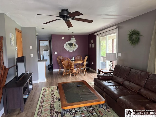 living area featuring baseboards, a ceiling fan, and wood finished floors