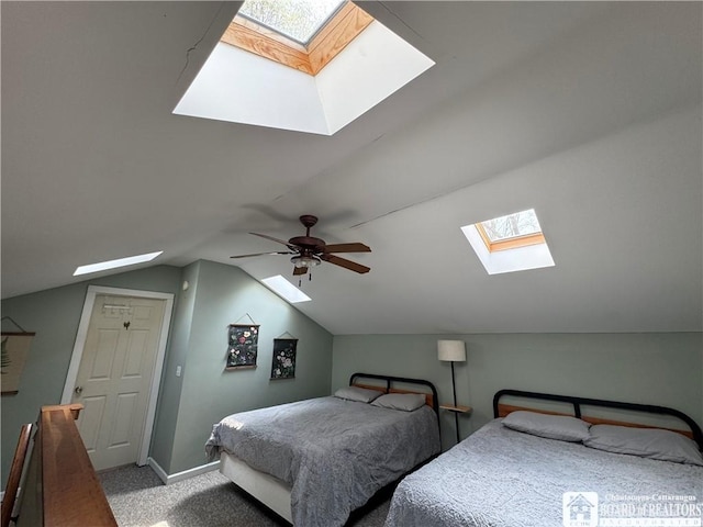 carpeted bedroom with vaulted ceiling with skylight, baseboards, and ceiling fan