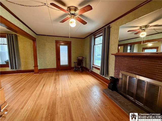 unfurnished living room with wood-type flooring, a ceiling fan, baseboards, and ornamental molding