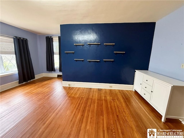 unfurnished room with baseboards, wood finished floors, and visible vents