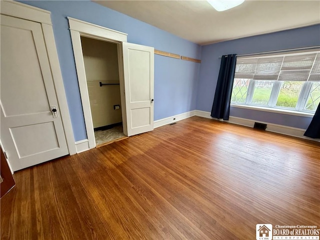 unfurnished bedroom with baseboards, visible vents, and wood finished floors