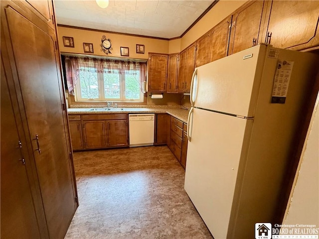 kitchen with brown cabinetry, a sink, white appliances, and ornamental molding