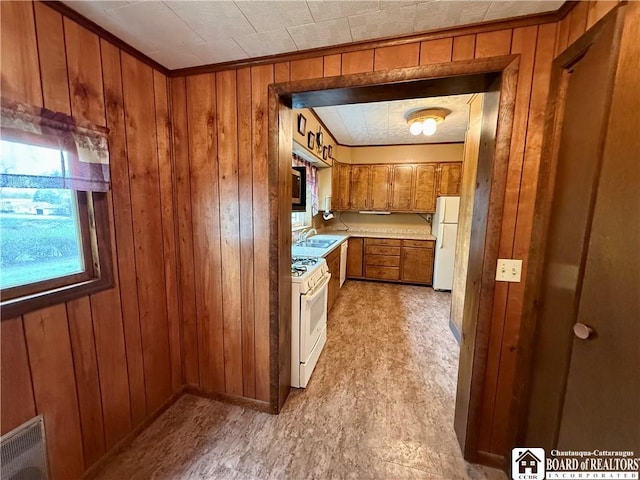 kitchen featuring a sink, white appliances, light countertops, wood walls, and brown cabinetry