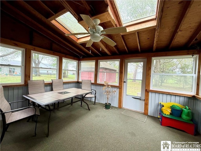sunroom featuring outdoor dining area, a ceiling fan, carpet, and lofted ceiling with skylight