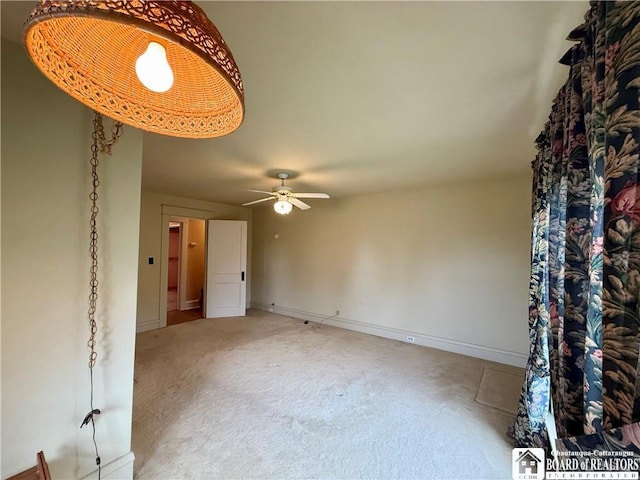 empty room featuring ceiling fan, light colored carpet, and baseboards