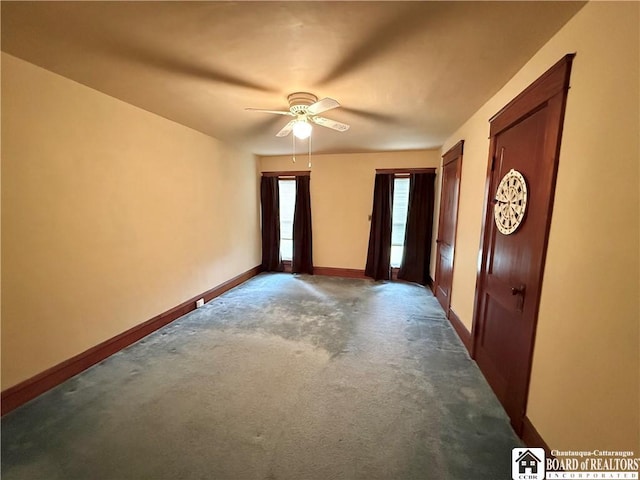 unfurnished room with carpet floors, a ceiling fan, and baseboards