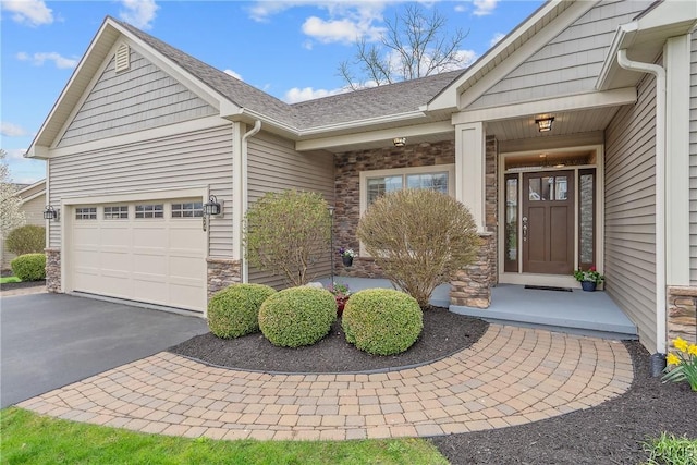 entrance to property featuring an attached garage, aphalt driveway, roof with shingles, and stone siding