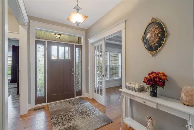 foyer entrance featuring visible vents, light wood-style flooring, and baseboards