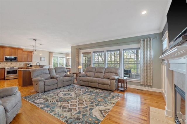 living room with visible vents, a fireplace with flush hearth, light wood-type flooring, ornamental molding, and recessed lighting