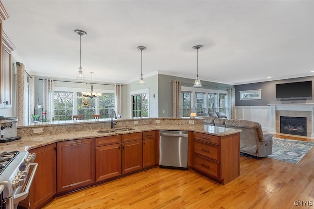 kitchen with brown cabinets, light stone countertops, appliances with stainless steel finishes, a sink, and light wood-style floors