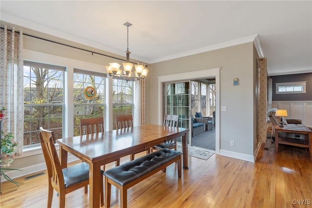 dining space with a healthy amount of sunlight, light wood finished floors, and a notable chandelier