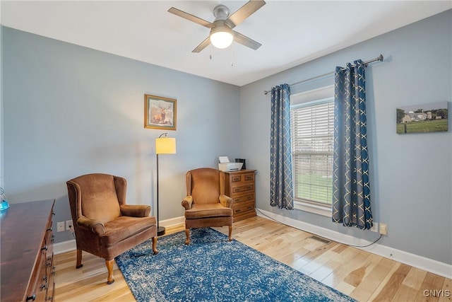 living area featuring light wood-style floors, baseboards, and a ceiling fan