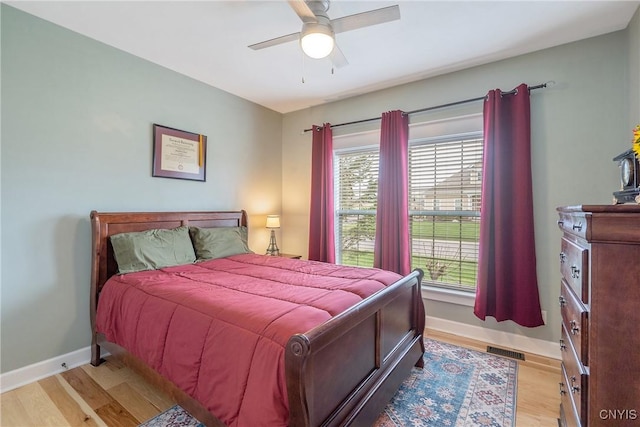 bedroom featuring baseboards, light wood-style flooring, and multiple windows