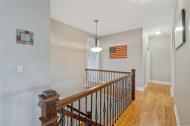 hall with baseboards, light wood finished floors, and an upstairs landing
