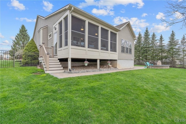 rear view of house with a lawn, fence, and a sunroom