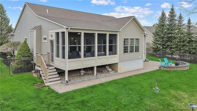 back of property with fence, a sunroom, a patio area, a lawn, and an outdoor fire pit