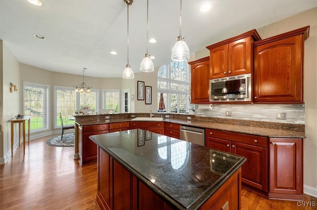 kitchen featuring stainless steel appliances, plenty of natural light, dark wood-type flooring, and a peninsula