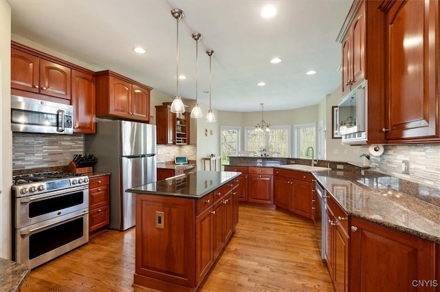 kitchen featuring a peninsula, light wood-style floors, tasteful backsplash, a sink, and stainless steel appliances