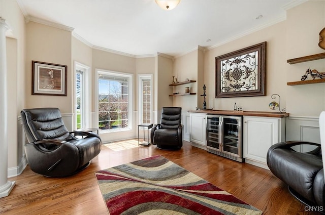 living area featuring crown molding, wine cooler, wood finished floors, and bar area