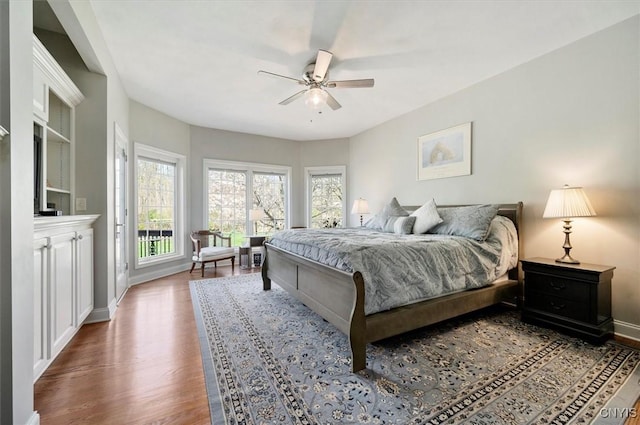 bedroom with baseboards, ceiling fan, multiple windows, and wood finished floors
