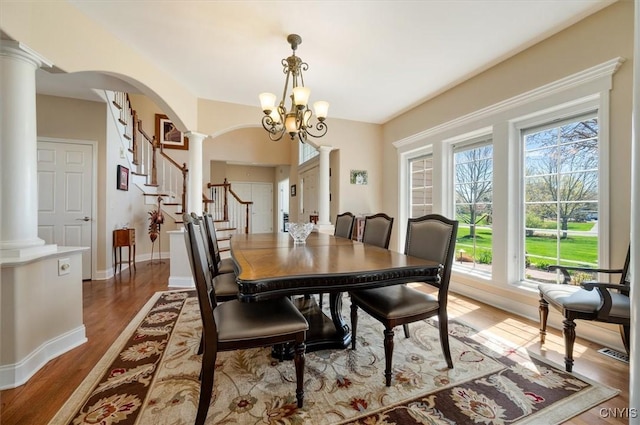 dining room featuring visible vents, arched walkways, wood finished floors, ornate columns, and stairs
