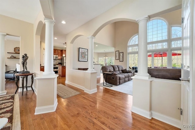 foyer entrance featuring light wood-style floors, arched walkways, and decorative columns
