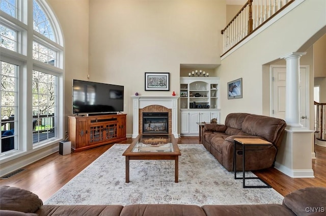 living area with visible vents, wood finished floors, and a towering ceiling