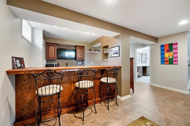 bar featuring baseboards, stainless steel microwave, recessed lighting, and wet bar