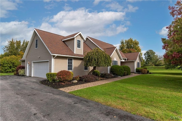 view of front of house featuring roof with shingles, driveway, and a front yard