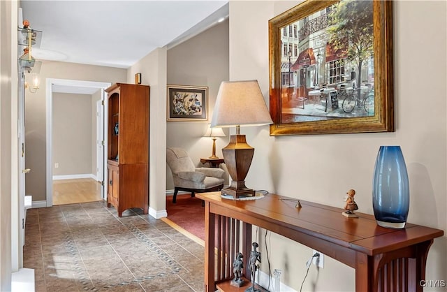hall featuring baseboards and stone finish floor