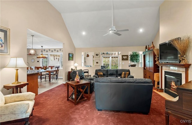 living area with a fireplace with flush hearth, high vaulted ceiling, a ceiling fan, and a wealth of natural light