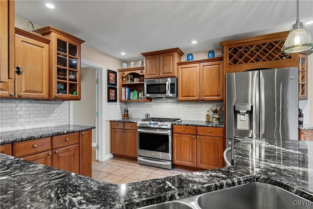 kitchen featuring brown cabinets, appliances with stainless steel finishes, decorative backsplash, and light tile patterned floors