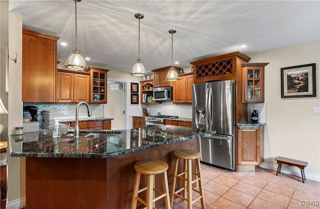 kitchen featuring brown cabinetry, a sink, a peninsula, and stainless steel appliances
