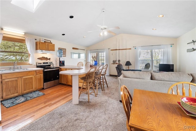 kitchen with a sink, a healthy amount of sunlight, a peninsula, and stainless steel range with electric cooktop