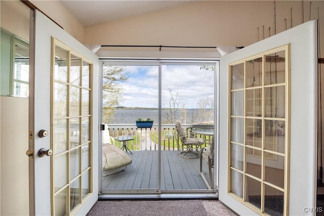 doorway featuring a water view, a wealth of natural light, carpet, and lofted ceiling